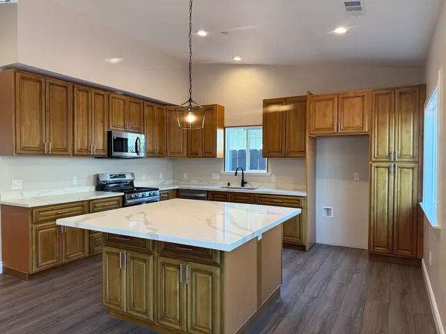 a kitchen that has a sink a microwave oven a stove and white cabinets with wooden floor