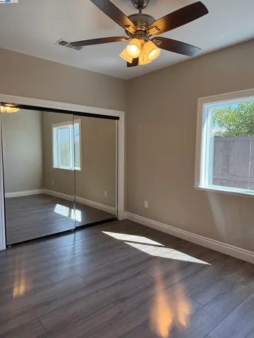 a view of empty room with wooden floor and fan