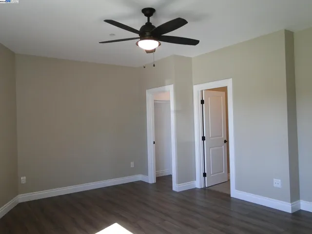 an empty room with wooden floor and a ceiling fan