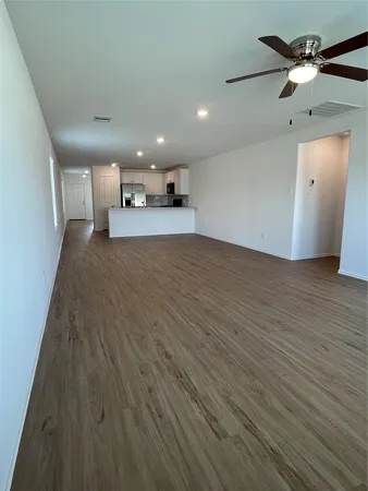 an empty room with wooden floor ceiling fan and windows