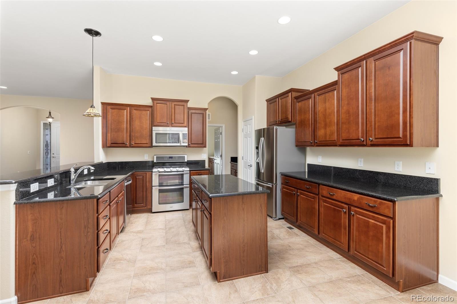 15965 Redcloud Way Broomfield, CO 80023 - Photo 12 of 49 a large kitchen with stainless steel appliances wooden cabinets a stove and a center island