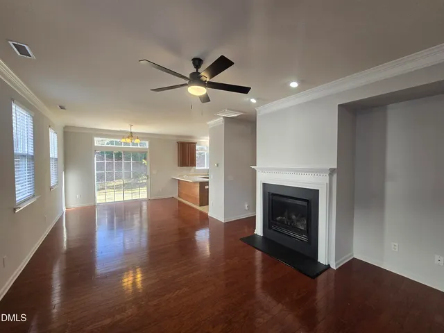 a view of an empty room with wooden floor fireplace and a window