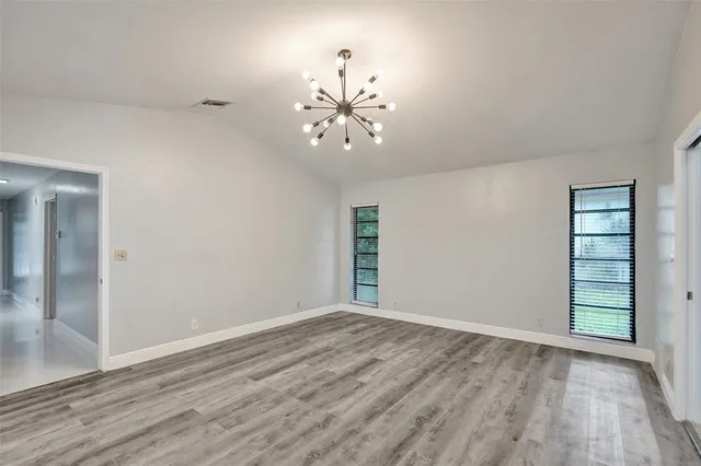 a view of an empty room with window and wooden floor