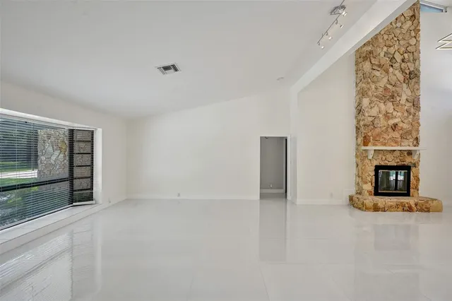 a view of an empty room with a fireplace and a window
