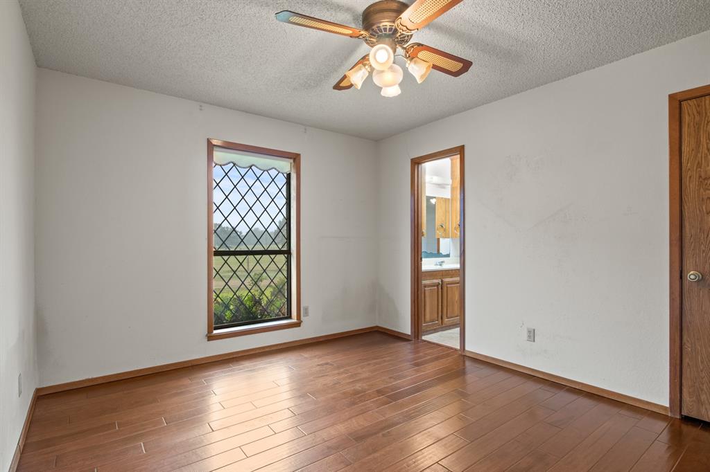 7777 Farm To Market 1001 Cookville, TX 75558 - Photo 20 of 30 an empty room with wooden floor chandelier fan and windows