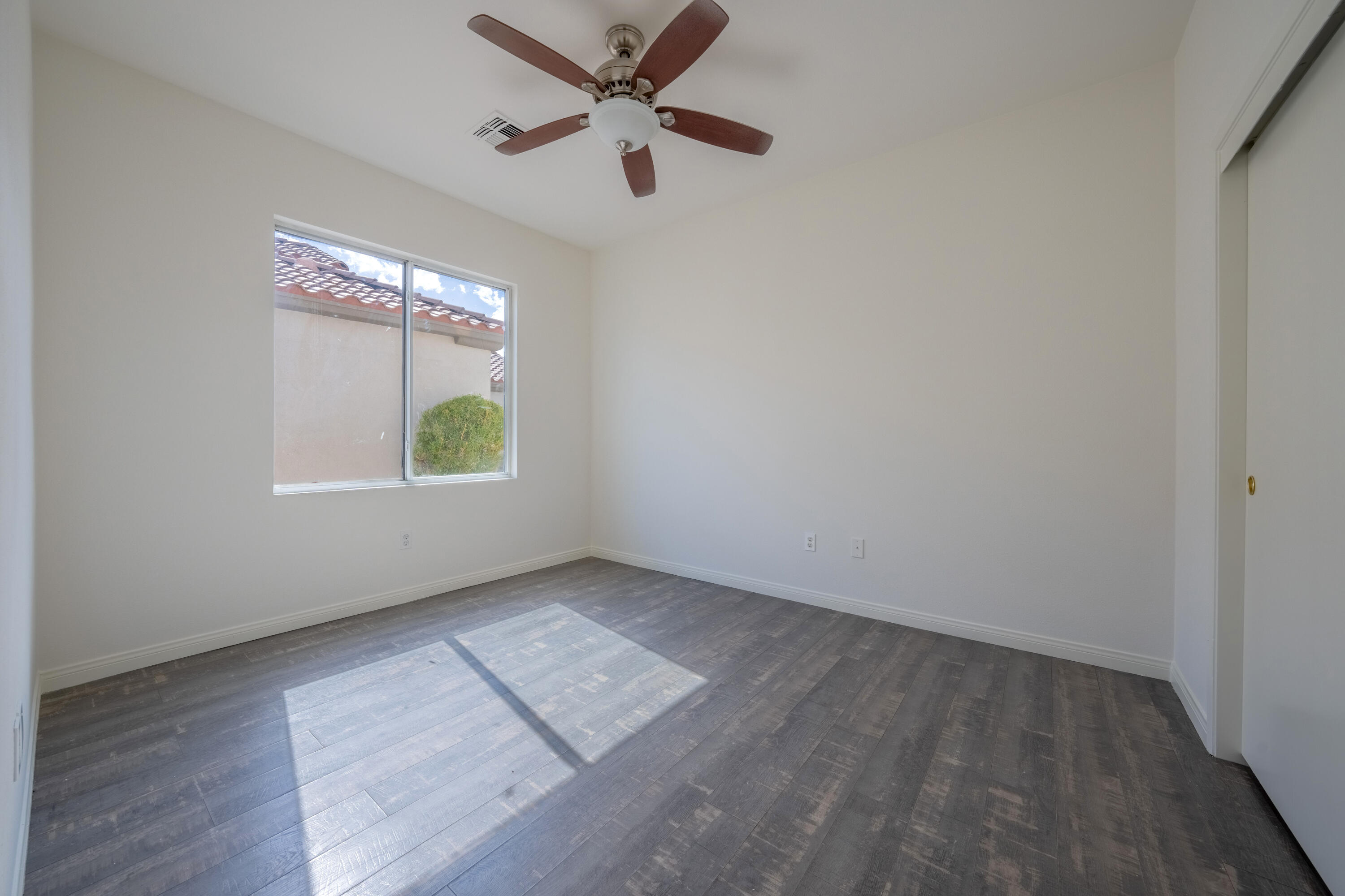 78640 Rainswept Way Palm Desert, CA 92211 - Photo 35 of 37 an empty room with wooden floor chandelier fan and windows