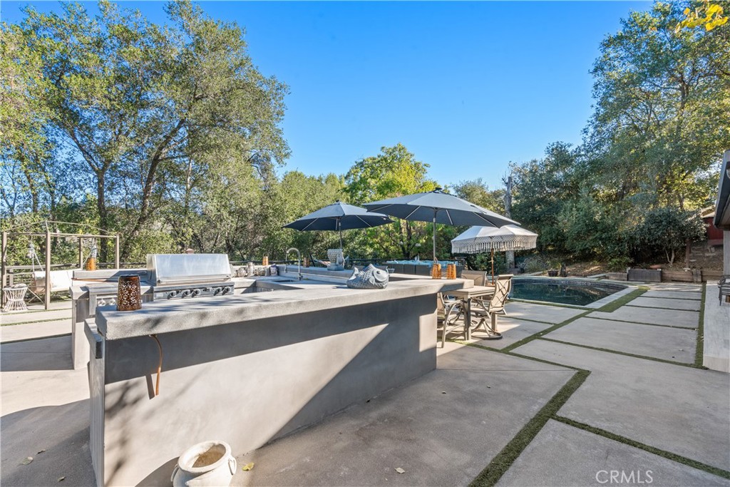 22 Round Up Road Bell Canyon, CA 91307 - Photo 33 of 39 a view of a patio with a dining table and chairs under an umbrella with large trees