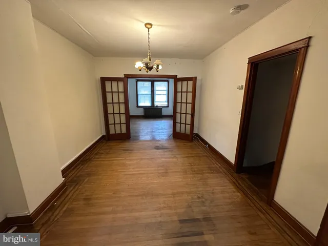 a view of a hallway with wooden floor and a kitchen space