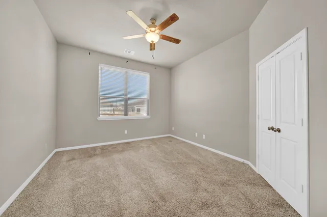 an empty room with windows and a ceiling fan