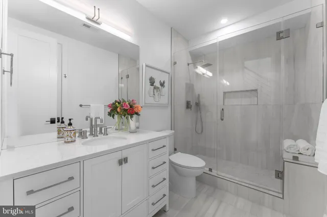 a bathroom with a shower sink vanity mirror and toilet