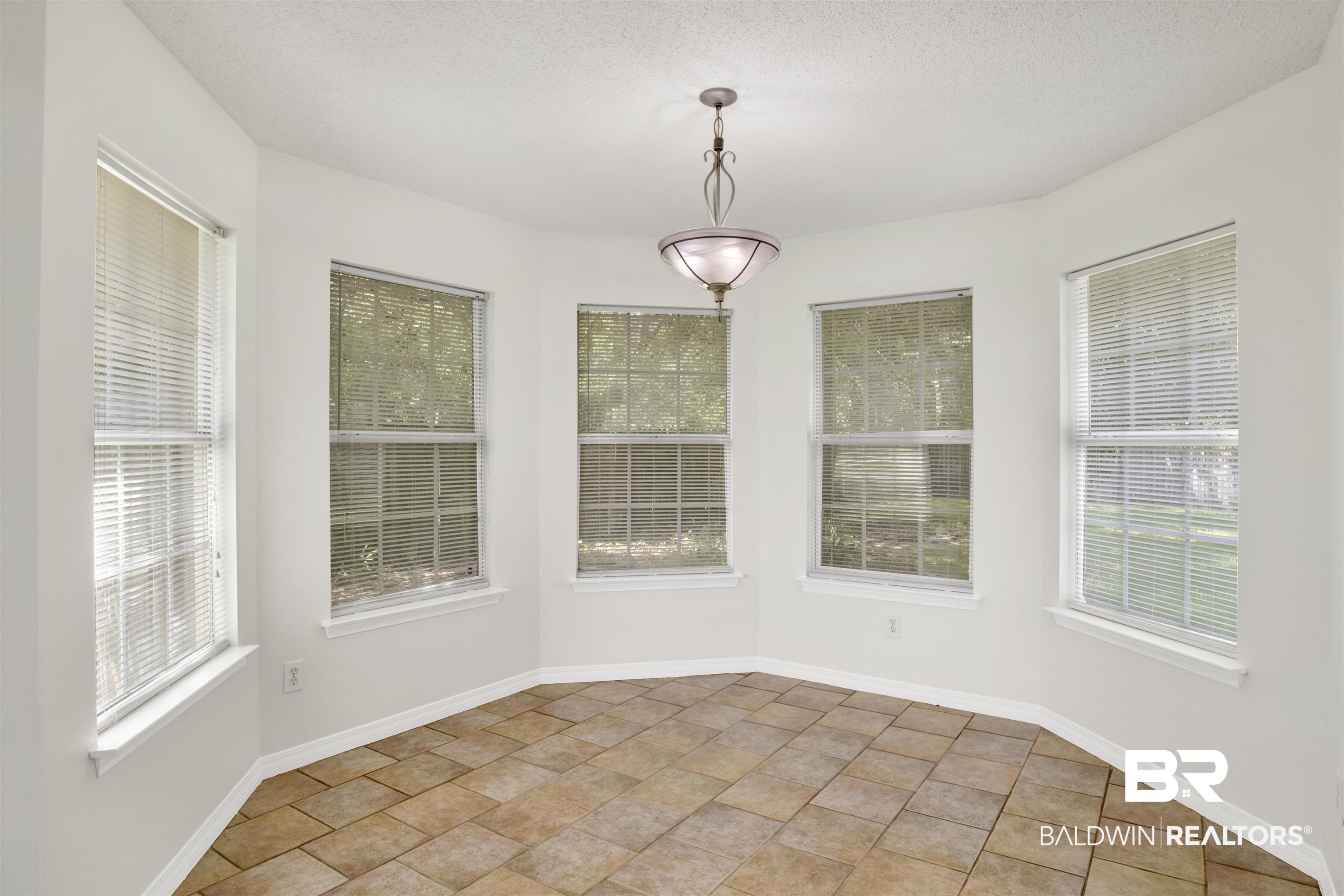 5480 Country Club Boulevard Theodore, AL 36582 - Photo 6 of 36 Unfurnished dining area with a wealth of natural light, light tile patterned flooring, and a textured ceiling