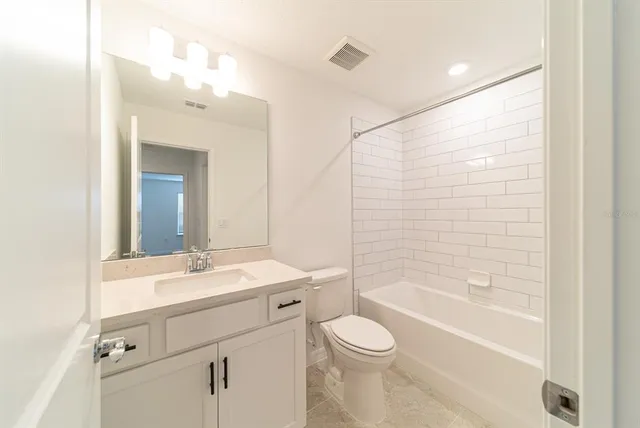 a bathroom with a bathtub shower sink vanity mirror and toilet