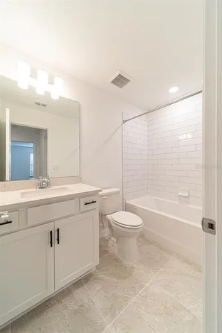 a bathroom with a granite countertop sink a toilet and bathtub