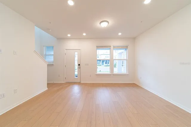 an empty room with wooden floor and windows