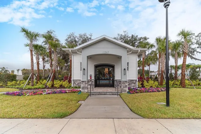 a view of a swimming pool with a patio and a yard with palm trees