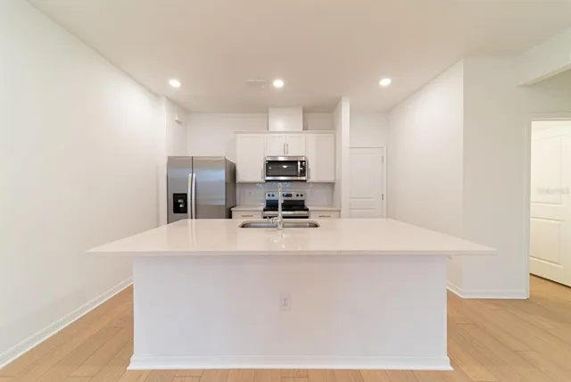 a large kitchen with stainless steel appliances a large counter top and a stove