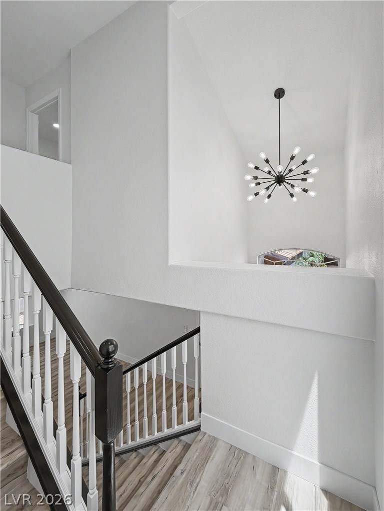 8977 Paige Rene Court Las Vegas, NV 89117 - Photo 25 of 31 A striking modern light fixture illuminates the multi-level staircase with wood flooring.