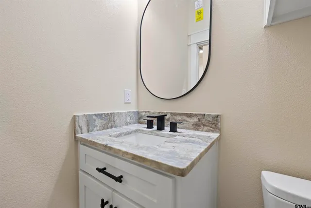 a bathroom with a granite countertop sink and a mirror