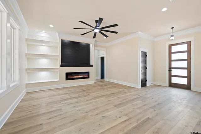 a view of empty room with wooden floor and fan
