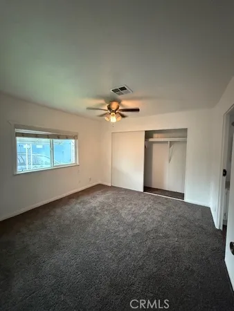 an empty room with a ceiling fan and window