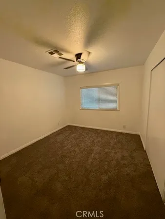 an empty room with a ceiling fan and window
