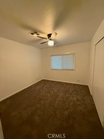 an empty room with a ceiling fan and window