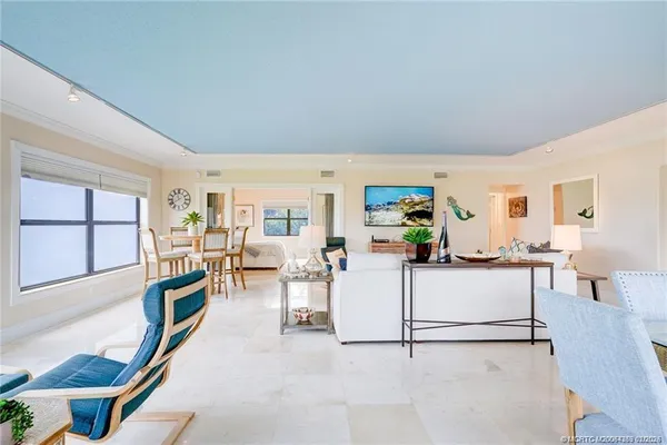 a living room with furniture a large window and kitchen view