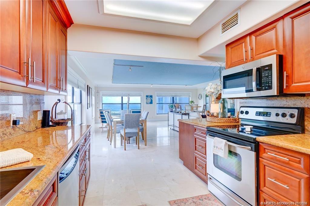1289 Northeast Ocean Boulevard, Unit 6 Stuart, FL 34996 - Photo 16 of 55 a kitchen with stainless steel appliances granite countertop a stove top oven a sink dishwasher a dining table and chairs with wooden floor