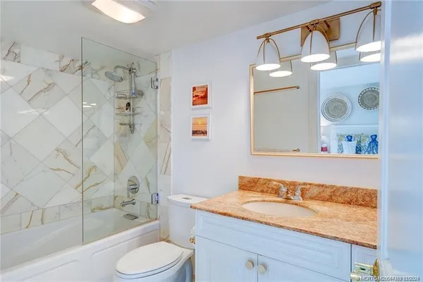 a bathroom with a granite countertop sink toilet and shower