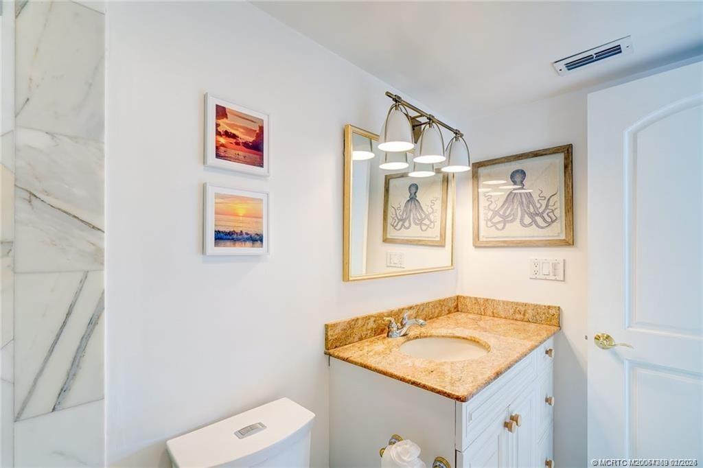 1289 Northeast Ocean Boulevard, Unit 6 Stuart, FL 34996 - Photo 23 of 55 a bathroom with a granite countertop sink and a mirror