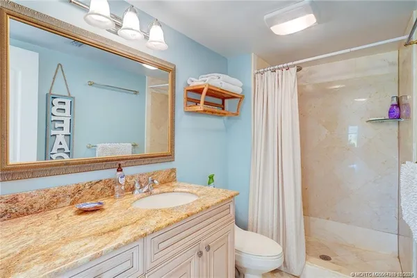a bathroom with a granite countertop sink toilet and shower
