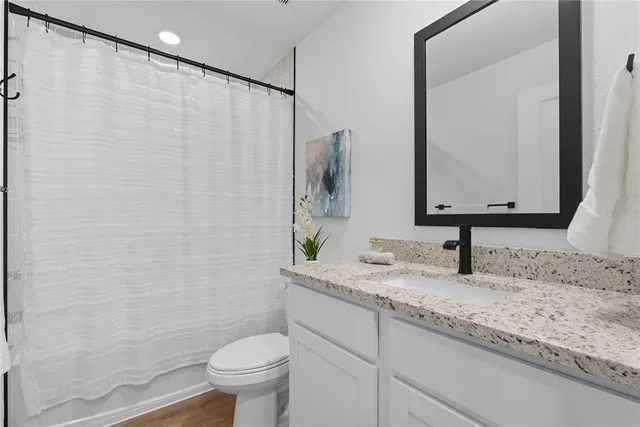 a bathroom with a granite countertop sink a toilet and a mirror