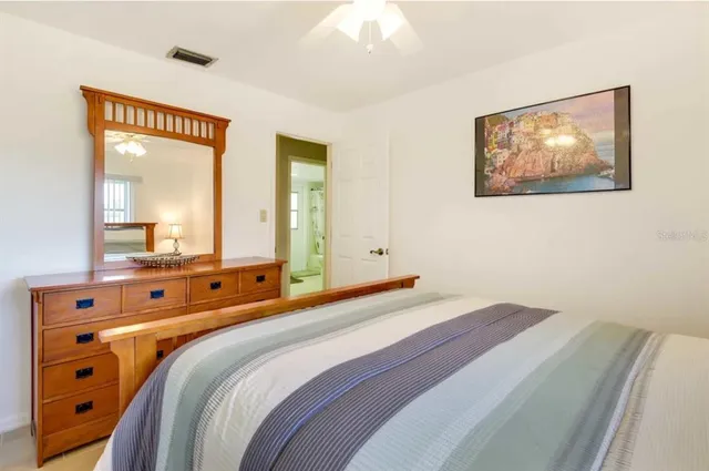 a bedroom with a bed and a large mirror on the dresser