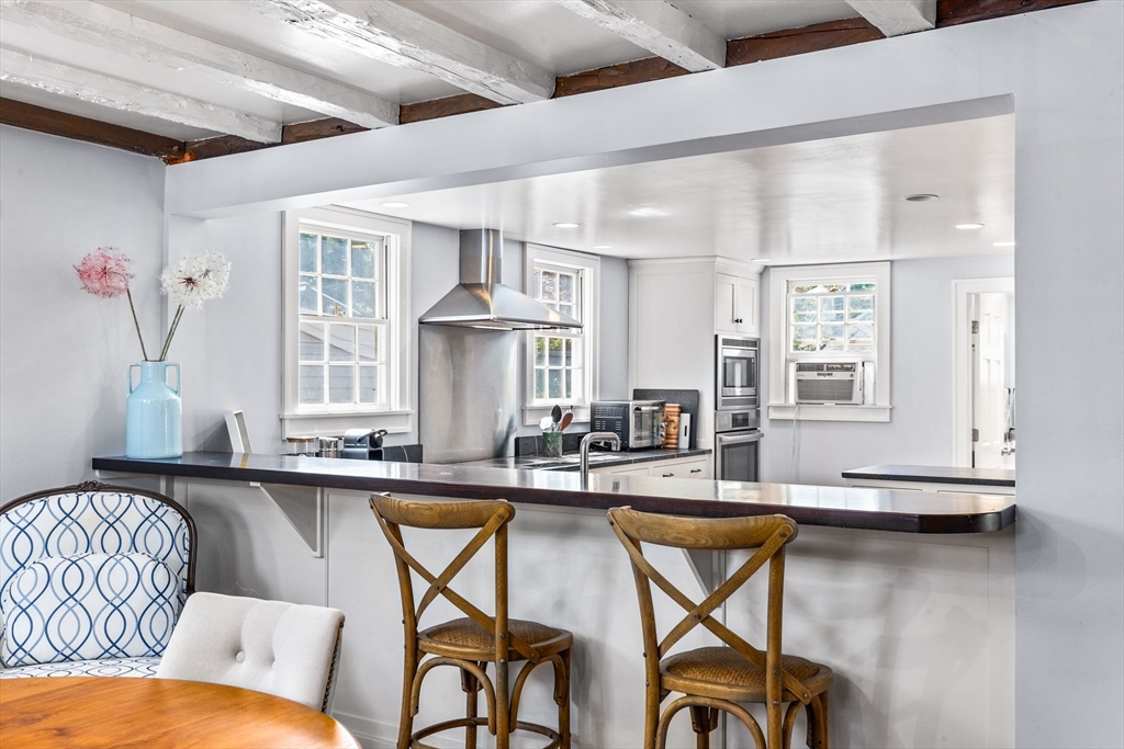 17 Pleasant Street Hingham, MA 02043 - Photo 16 of 41 a kitchen with stainless steel appliances granite countertop a table chairs in it and wooden floors