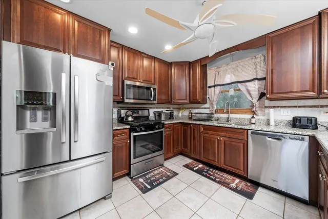a kitchen with granite countertop a refrigerator stove top oven a sink and dishwasher