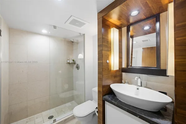 a bathroom with a sink a toilet a mirror and shower