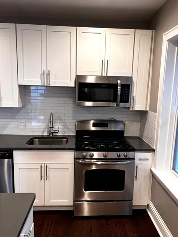 a kitchen with white cabinets and black appliances