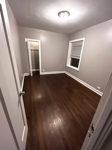 a view of an empty room with wooden floor and stairs