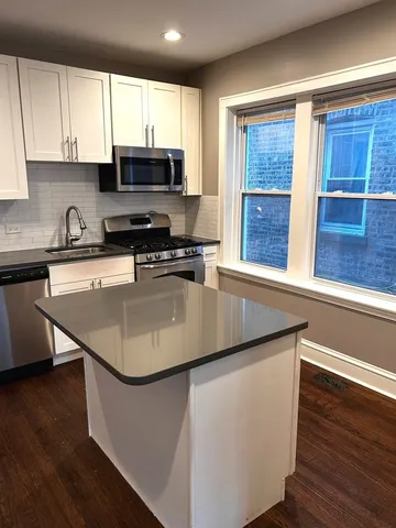a kitchen with stainless steel appliances granite countertop a sink a stove and a microwave with wooden floor