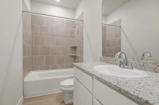 a bathroom with a granite countertop sink a toilet and bathtub