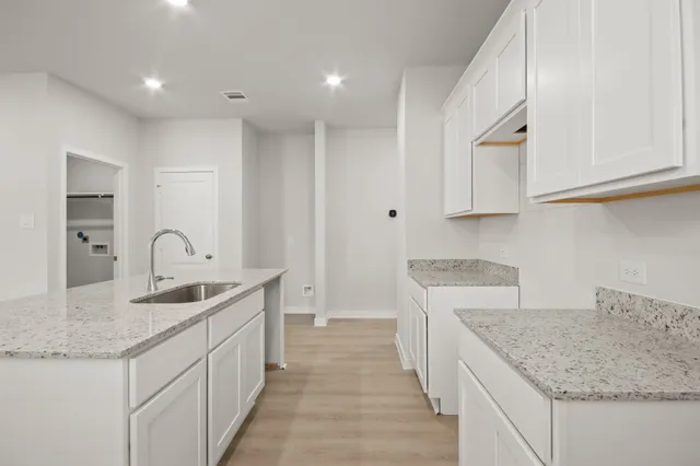 a kitchen with granite countertop a sink and white cabinets