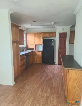 a kitchen with stainless steel appliances granite countertop a refrigerator a sink dishwasher a stove and white countertops with wooden floor