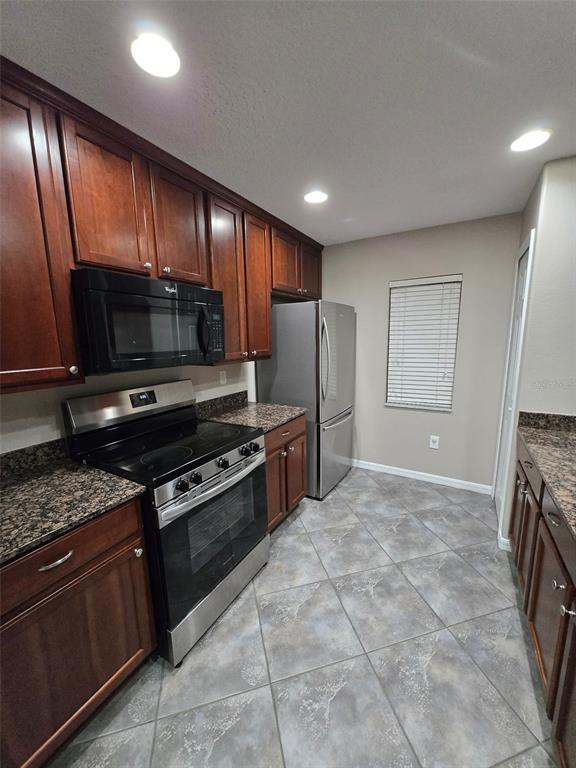 12905 Trade Port Place Riverview, FL 33579 - Photo 8 of 14 a kitchen with stainless steel appliances granite countertop a stove a sink and a microwave