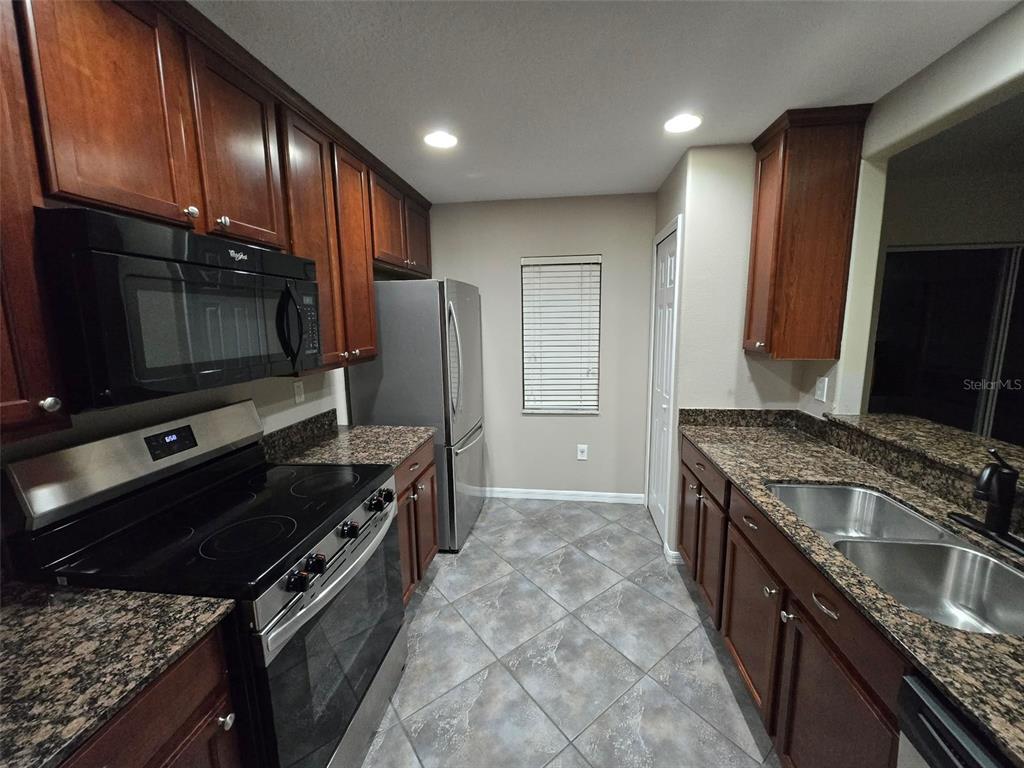 12905 Trade Port Place Riverview, FL 33579 - Photo 9 of 14 a kitchen with stainless steel appliances granite countertop a stove top oven microwave and refrigerator