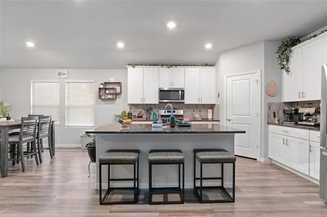 a kitchen with stainless steel appliances a table chairs refrigerator microwave and cabinets