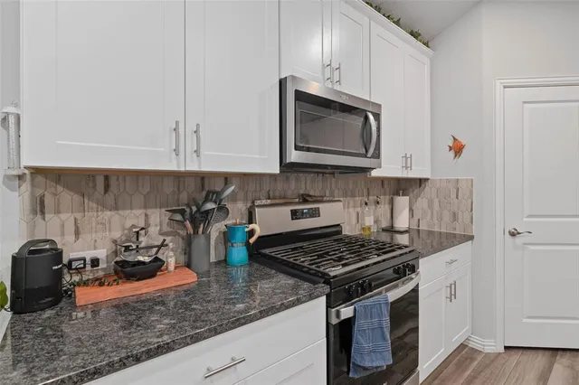 a kitchen with granite countertop a stove sink and cabinets