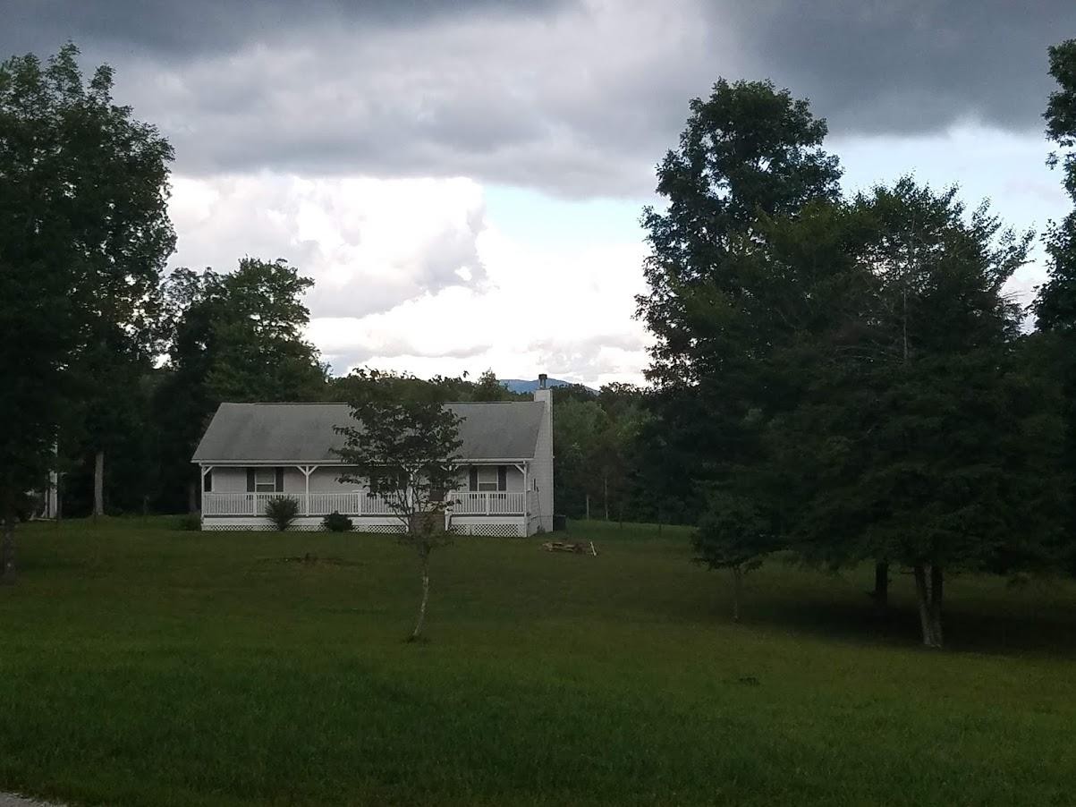 467 Ridge Road Lancing, TN 37770 - Photo 5 of 40 a view of a white house with a big yard and large trees