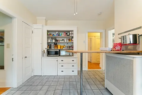 a kitchen with white cabinets and window