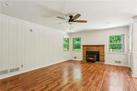 an empty room with windows fireplace and wooden floor