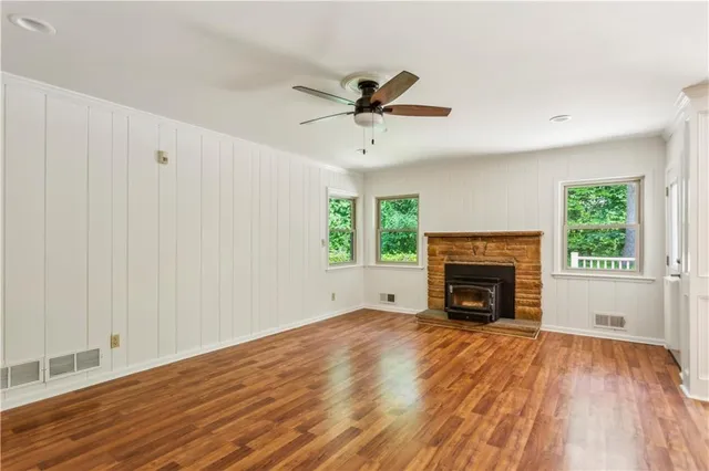 an empty room with windows fireplace and wooden floor